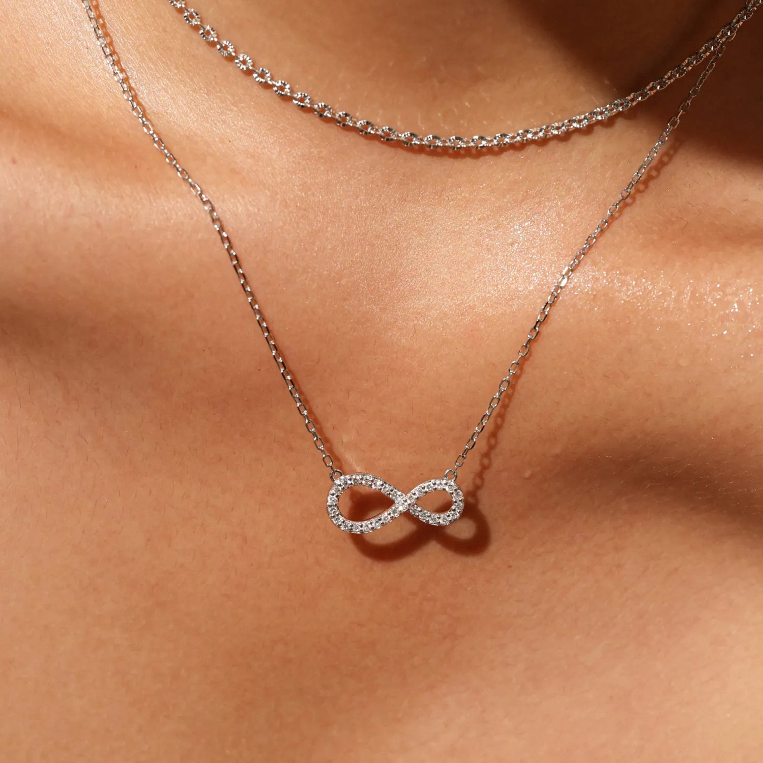 Agvana Silver infinity necklace on a person's neck against a neutral background