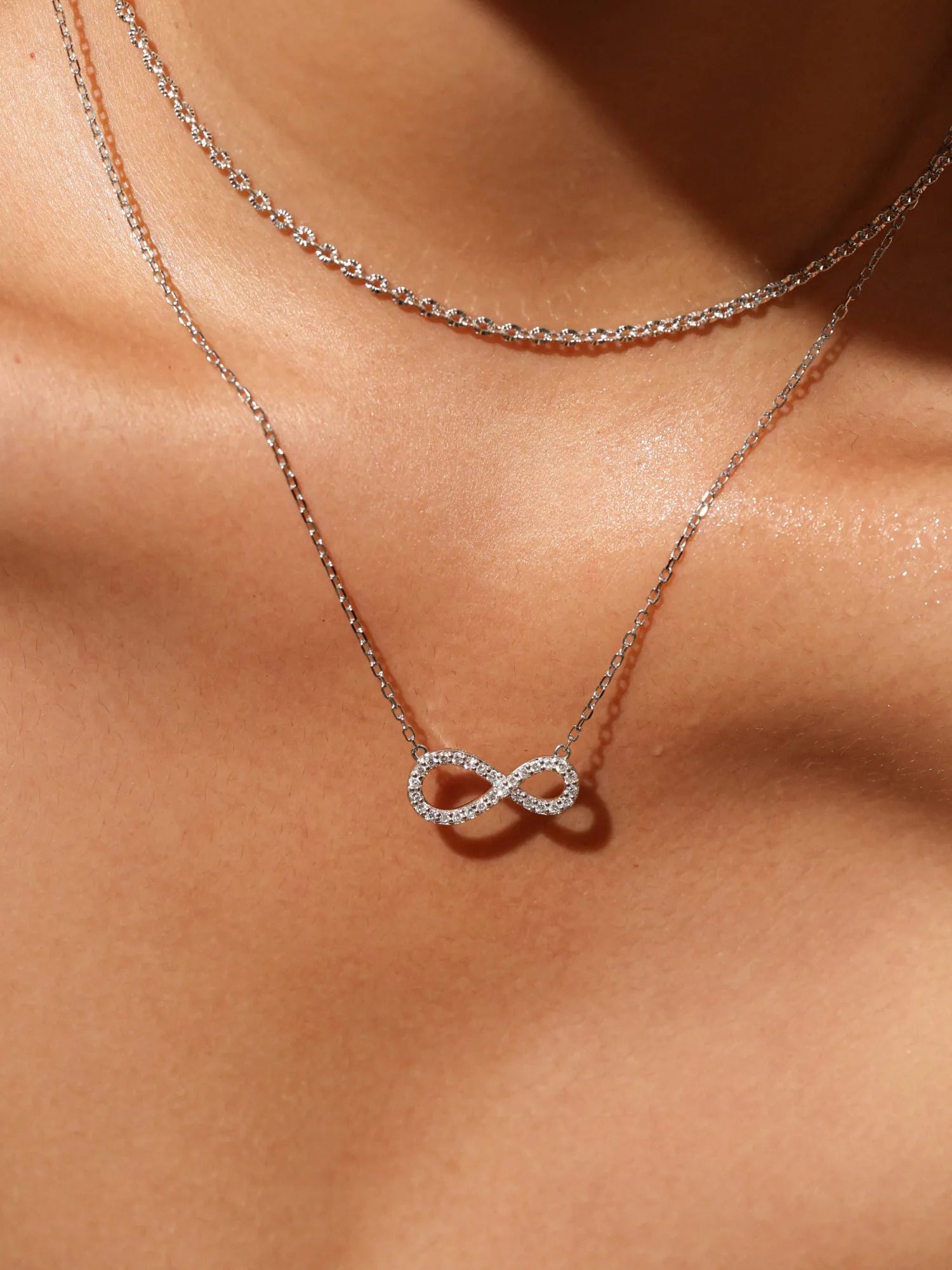 Agvana Silver infinity necklace on a person's neck against a neutral background
